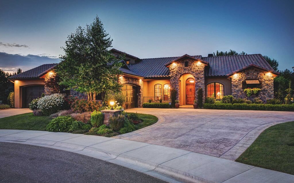 Stone and stucco home lit at dusk with a circular drive