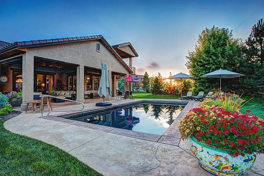 Pool and covered patio behind a stone and stucco home